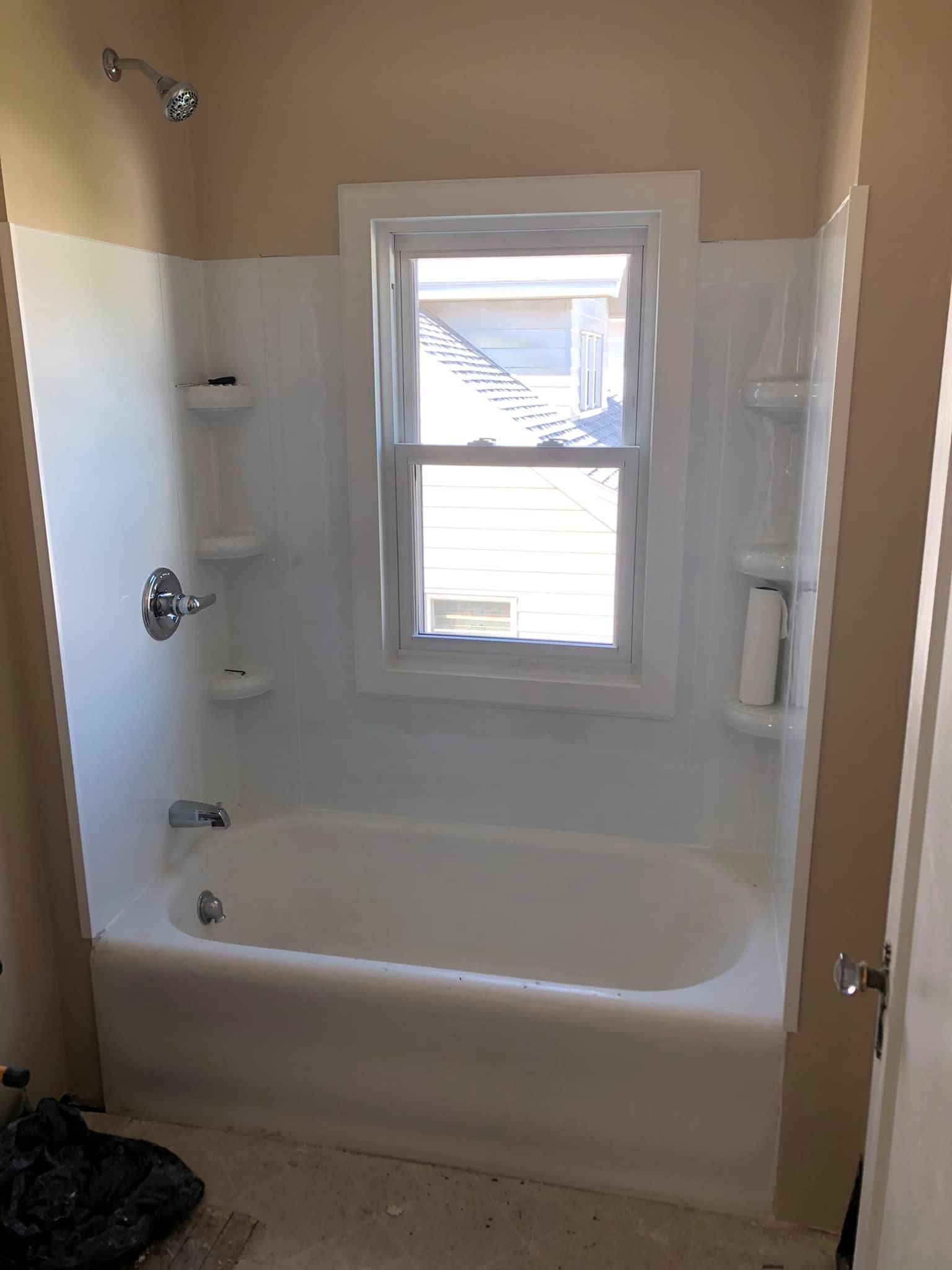 A bathroom with a bathtub , shower , and window.