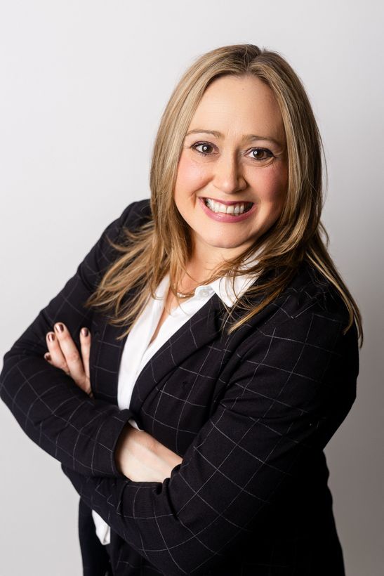 A woman is sitting at a desk with a laptop and a vase of flowers.