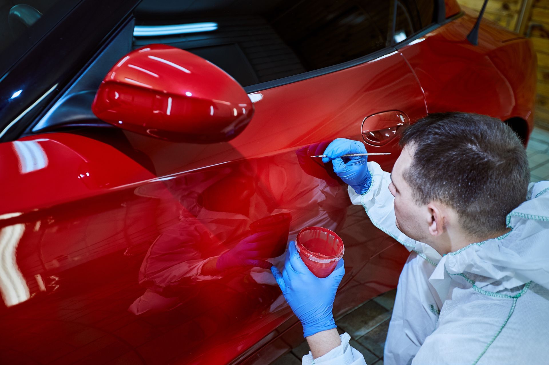 a man is painting a red car with a brush .