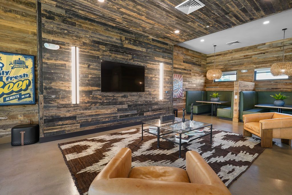 Modern community lounge with a wall-mounted TV, wood-paneled walls, and cozy seating.