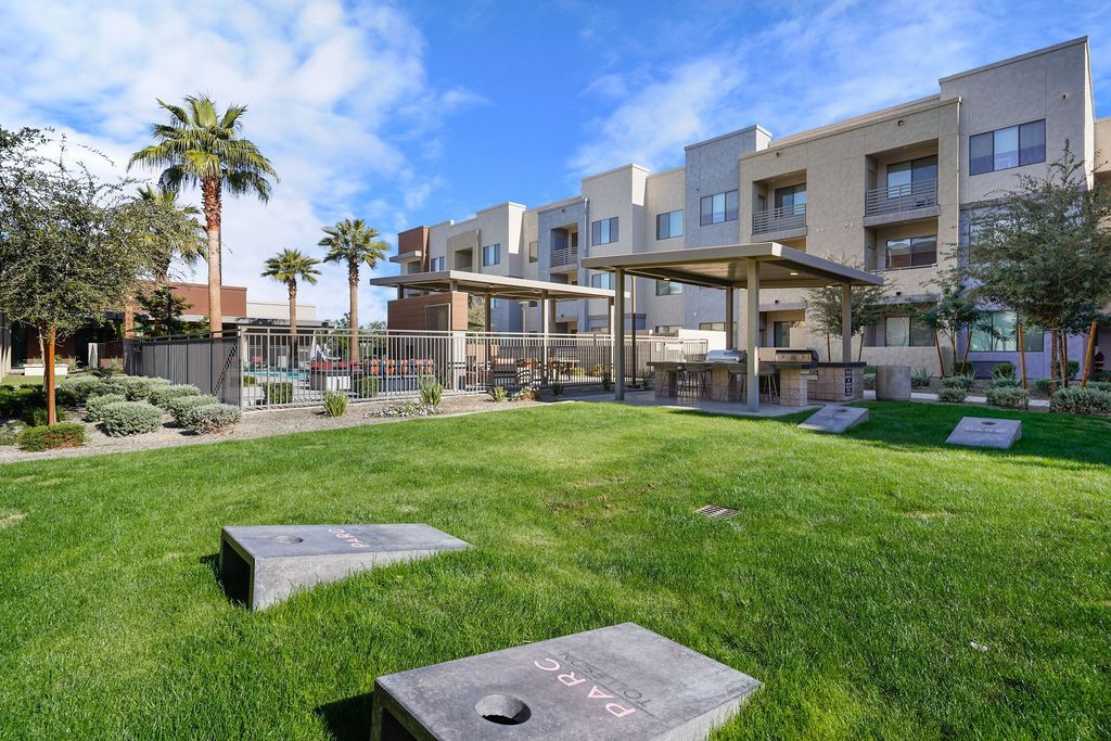 Exterior view of a modern apartment community courtyard with lawn and grilling area.