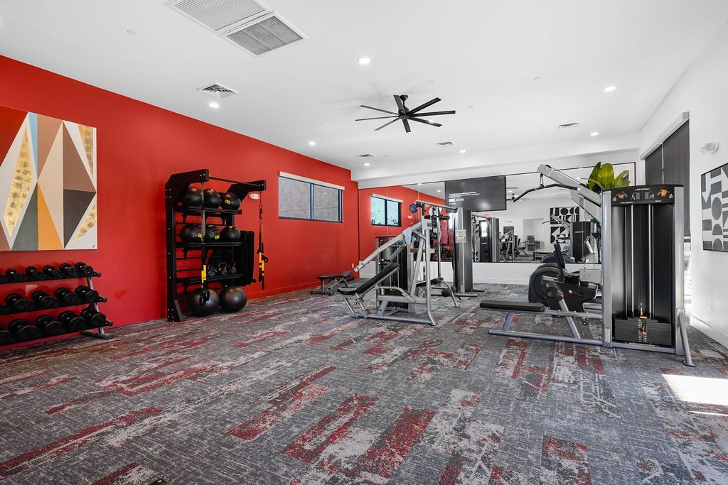 Fitness center with red accent wall, free weights, and multi-station gym equipment.