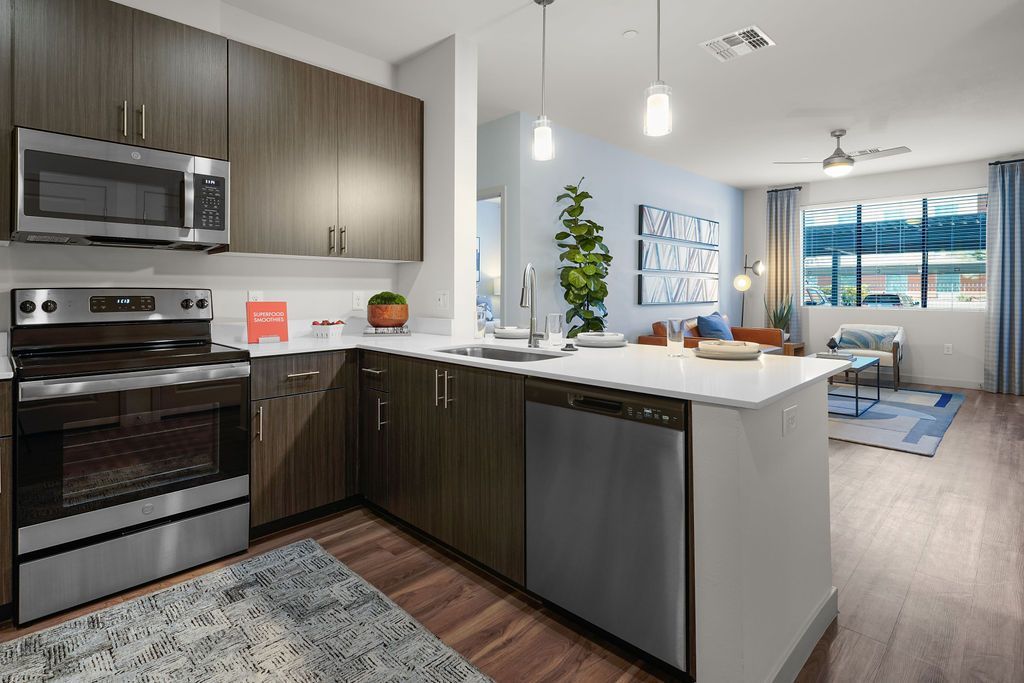Open-concept kitchen with dark wood cabinets, stainless steel appliances, and a white island.