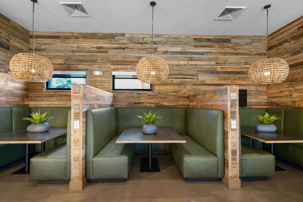 Booth seating in a wood-paneled dining area with green benches and pendant lights.