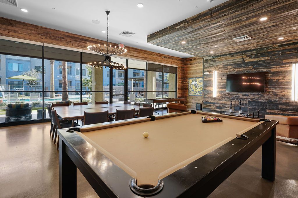 Communal recreation room with pool table, lounge seating, and large windows.