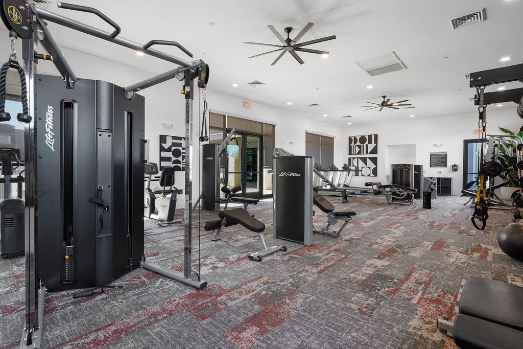 Indoor apartment community gym with weight machines and cardio equipment.
