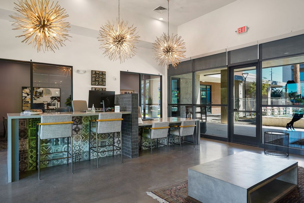 Modern apartment lobby with a reception desk, seating, and large glass doors to an outdoor area.