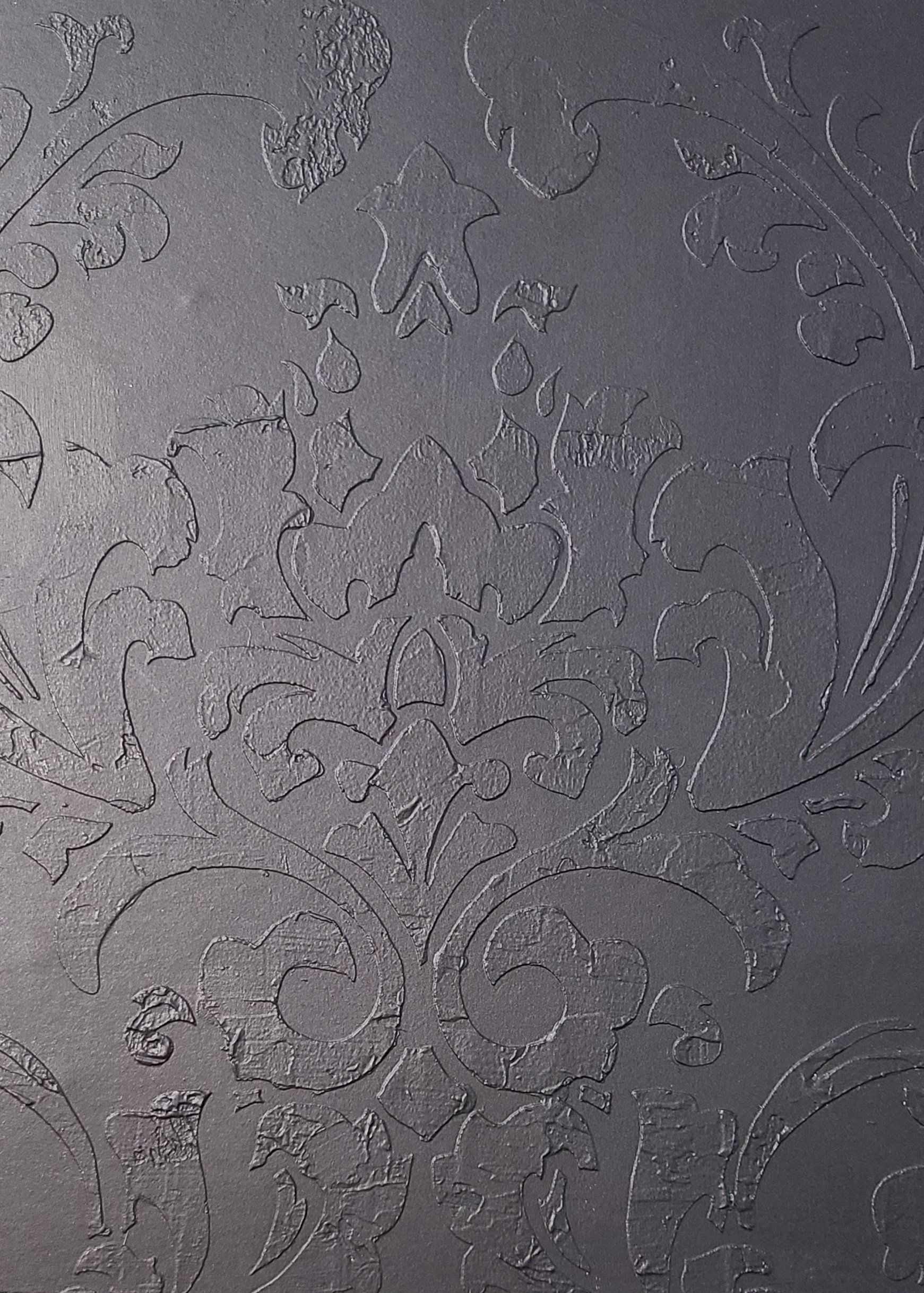 Dark gray textured wall with floral damask pattern.