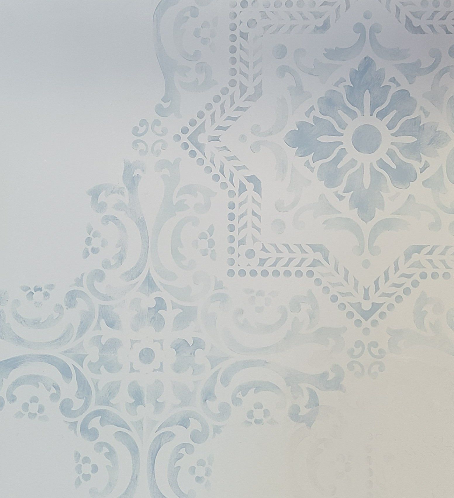 Light blue patterned stencil design on a white wall.