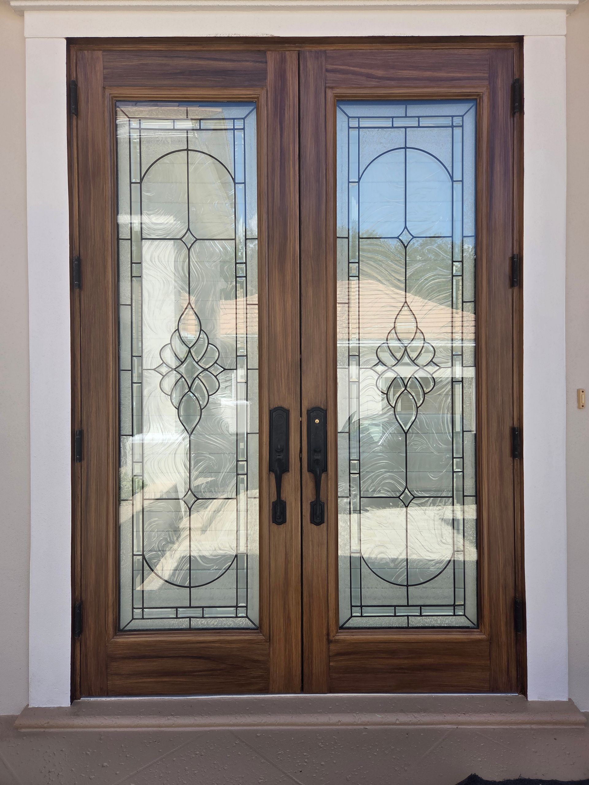 Wooden double doors with glass panels and decorative black lines.