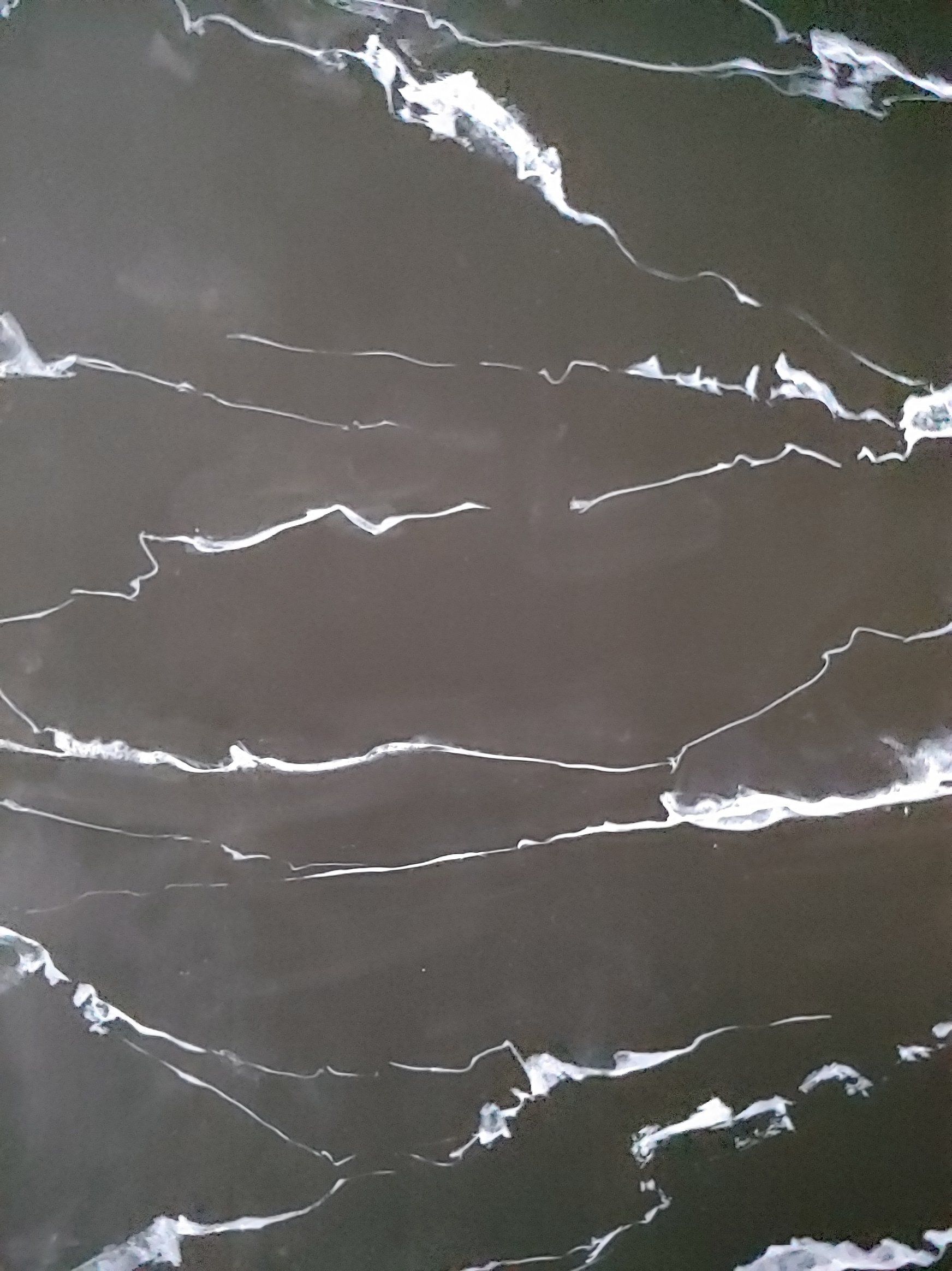 Dark gray surface with white vein-like patterns.
