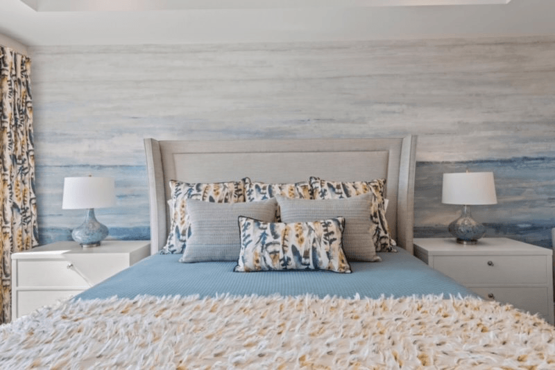 Bedroom with a blue bed, white nightstands, and blue and white wall mural.