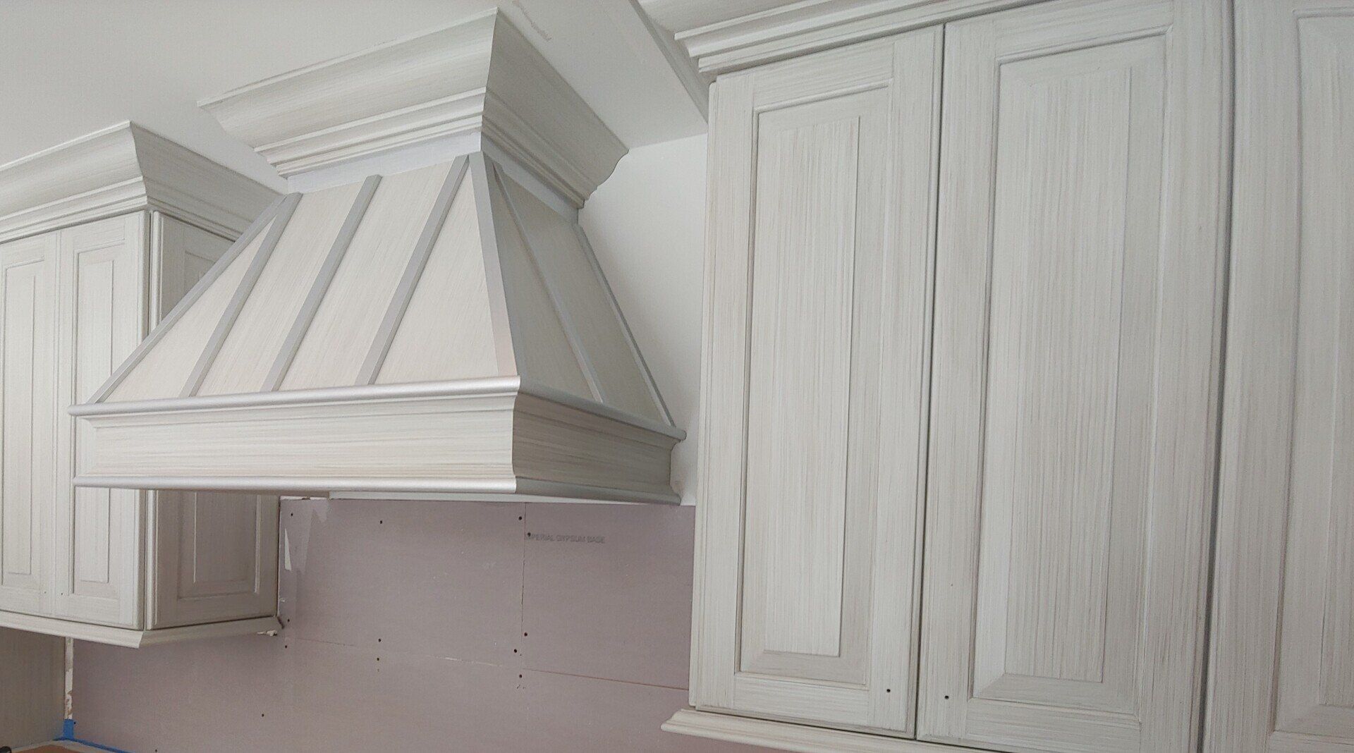 White distressed kitchen cabinets and range hood.