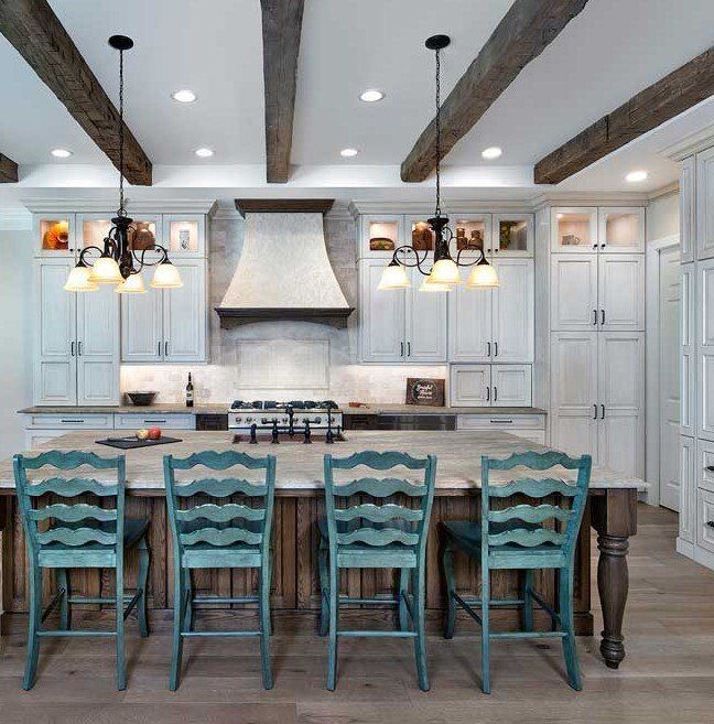 Kitchen with teal bar stools, white cabinets, wooden beams, and pendant lights.