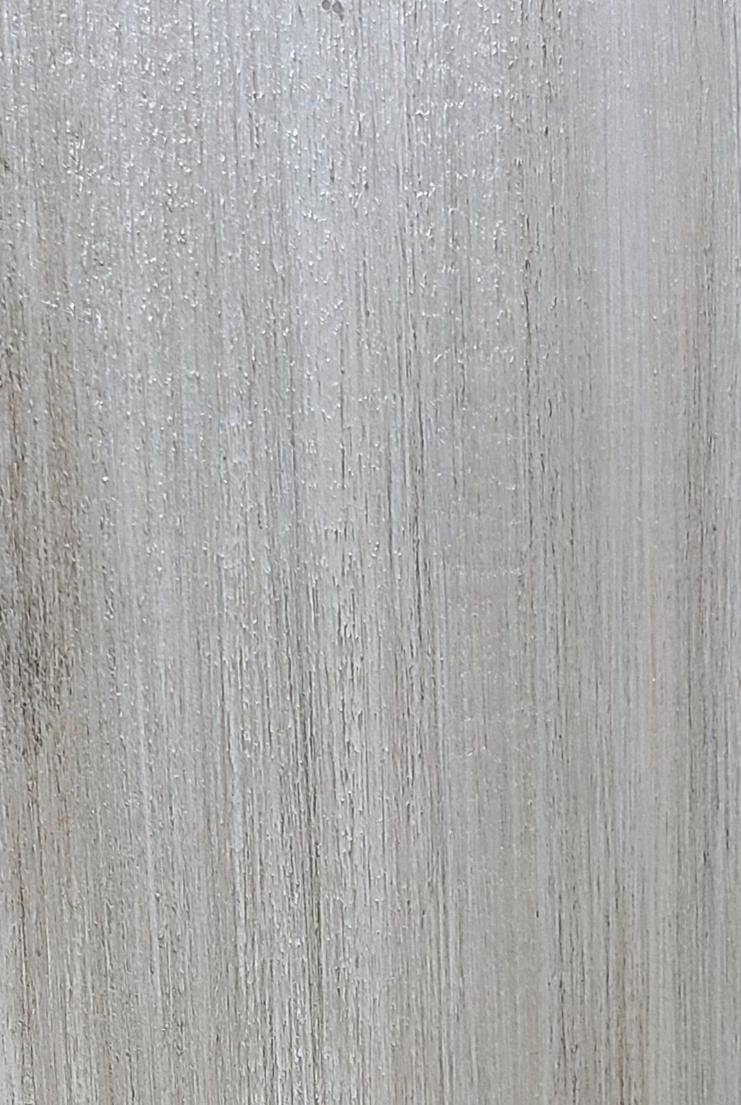 Close-up of textured, light gray wood grain with vertical streaks and subtle highlights.