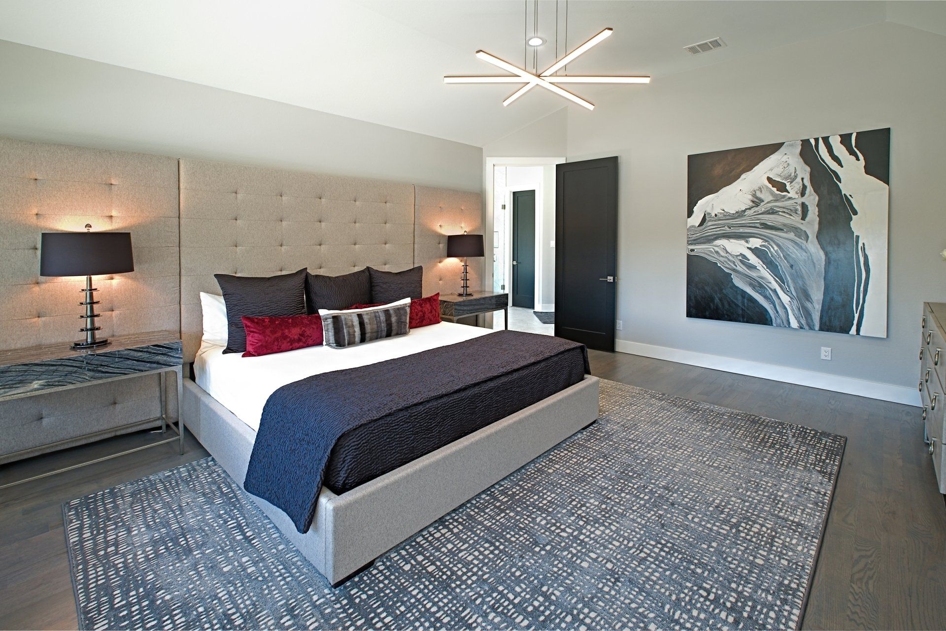 a bedroom with a large bed and a painting on the wall with dramatic black and white interior design