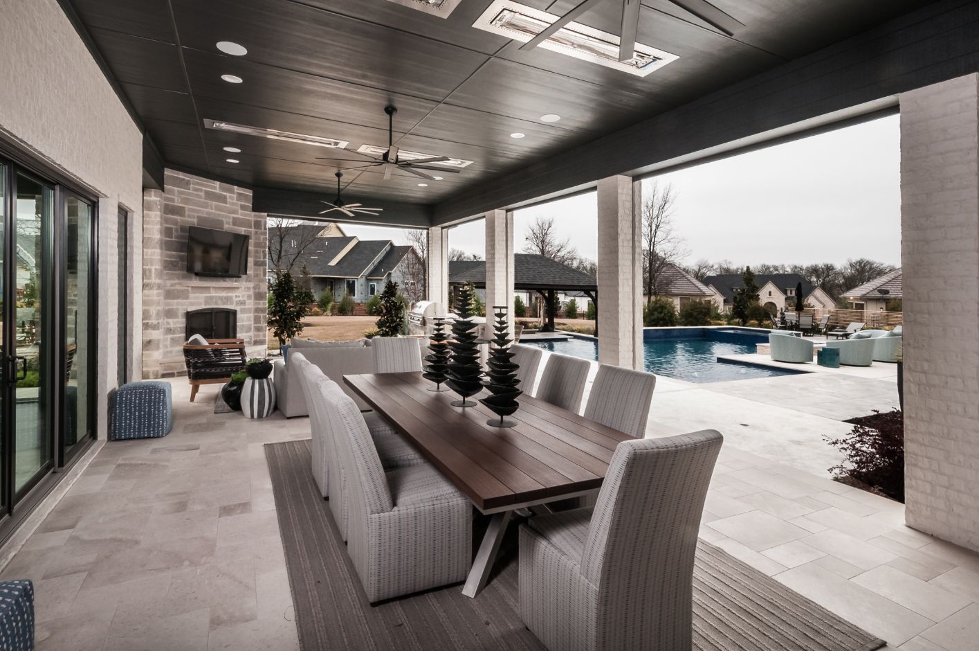 A large patio with a dining table and chairs and a swimming pool.