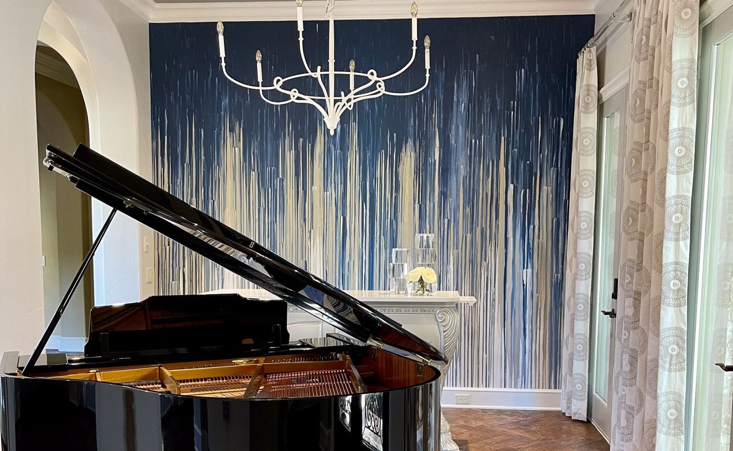 A piano room with a chandelier and a stunning blue and cream handpainted wallcovering.