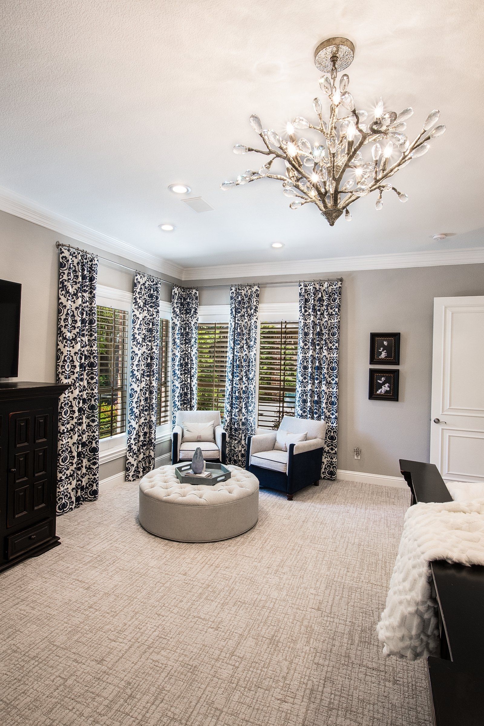 a master suite with a chandelier hanging from the ceiling and black and white window treatments