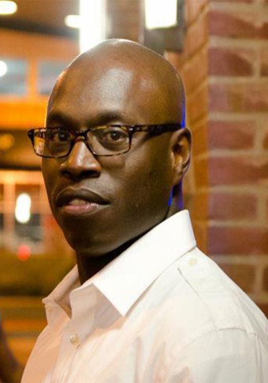 A bald man wearing glasses and a white shirt