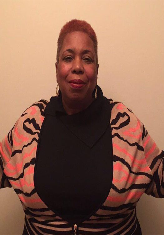 A woman wearing a striped sweater and a black turtleneck is smiling for the camera.