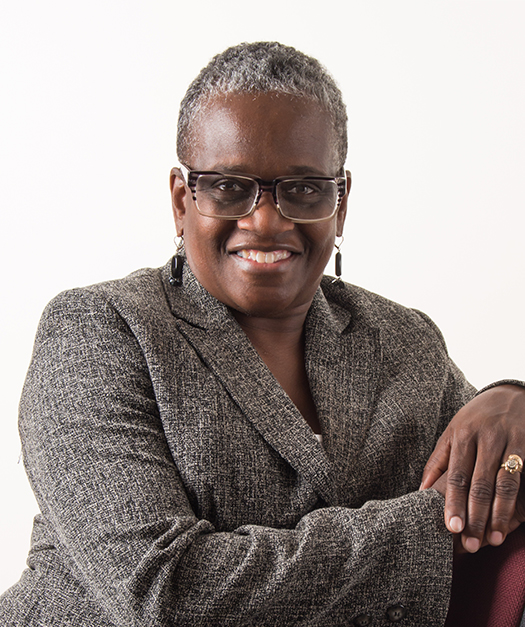 A woman wearing glasses and a suit is smiling for the camera.