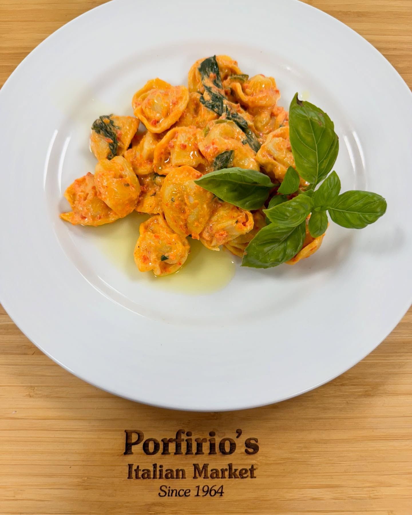 A white plate topped with pasta and basil from porfirio 's italian market