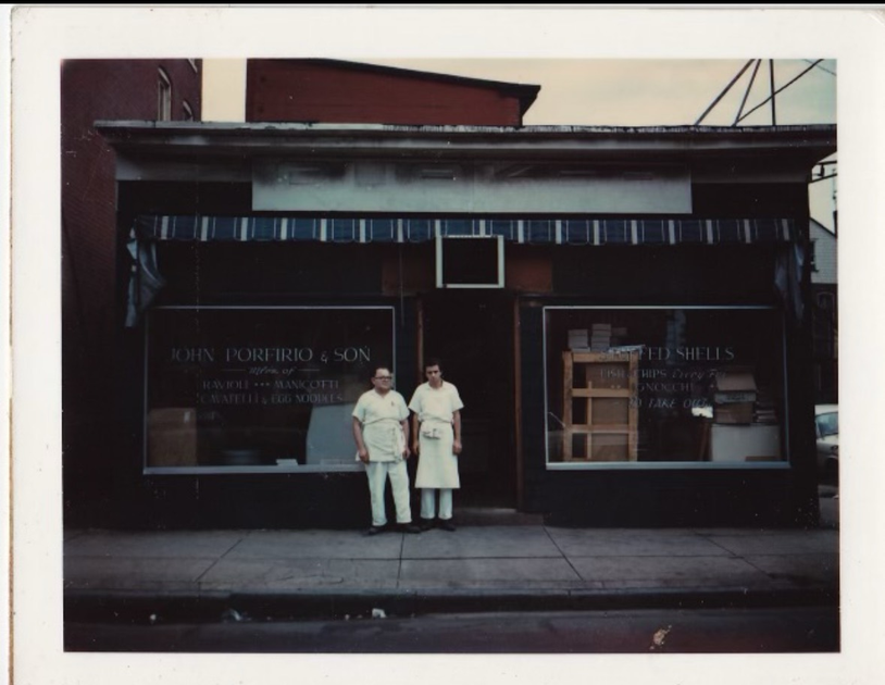 Two people standing in front of a store that says ' the angels ' on it