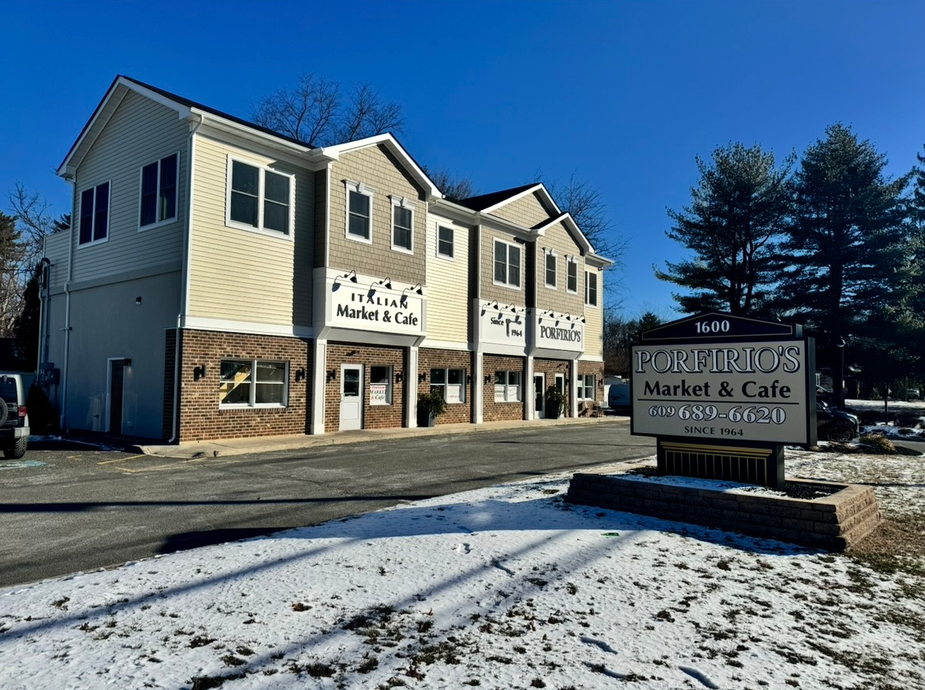 A building with a sign in front of it and snow on the ground.