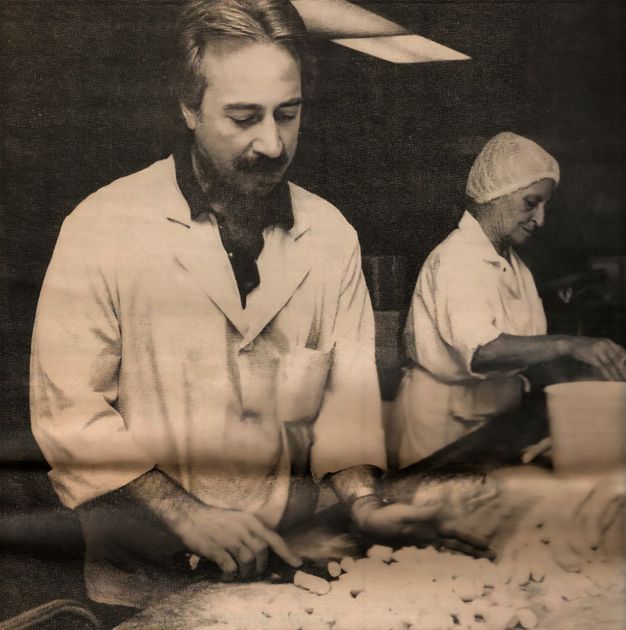 A black and white photo of a man and woman preparing food