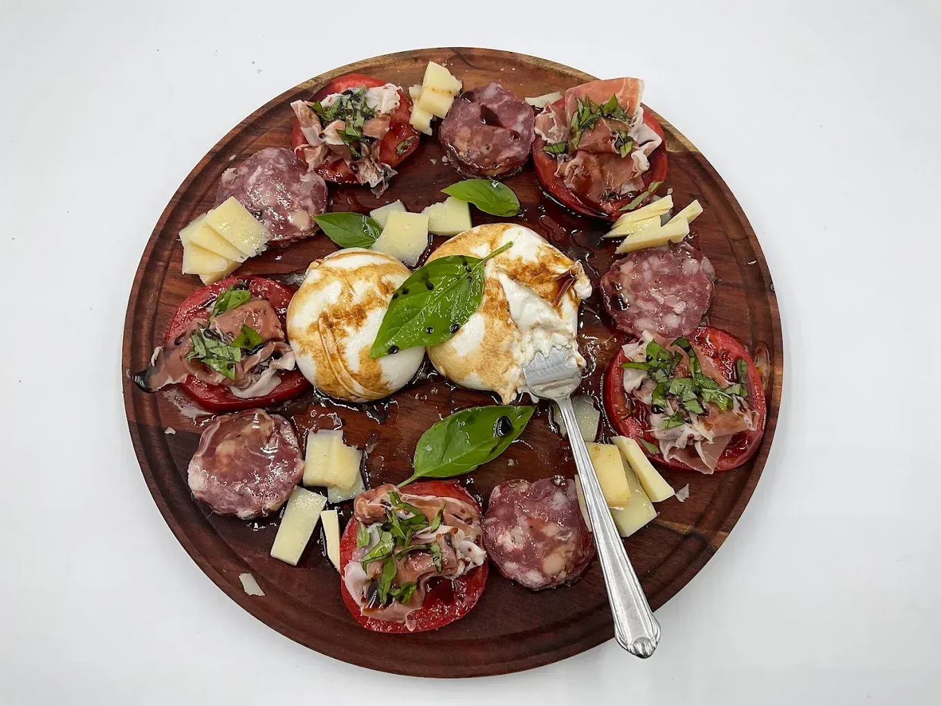 A wooden cutting board topped with a variety of food and a fork.