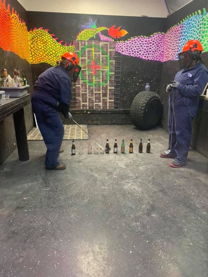 Two men are playing a game in a room with bottles on the floor.