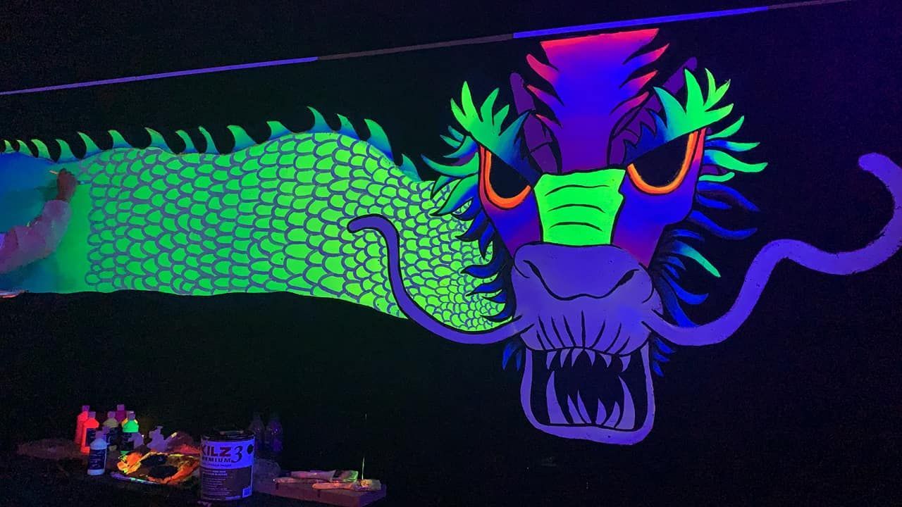 A glow in the dark dragon is painted on a wall.