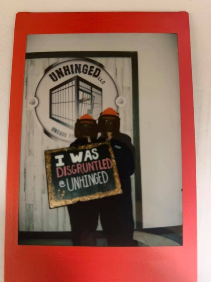 Two people holding a sign that says i was disgruntled and unhinged