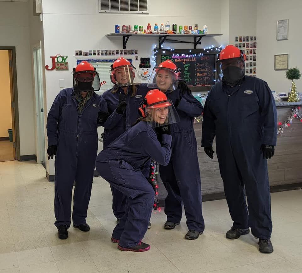 A group of people wearing hard hats and overalls pose for a picture
