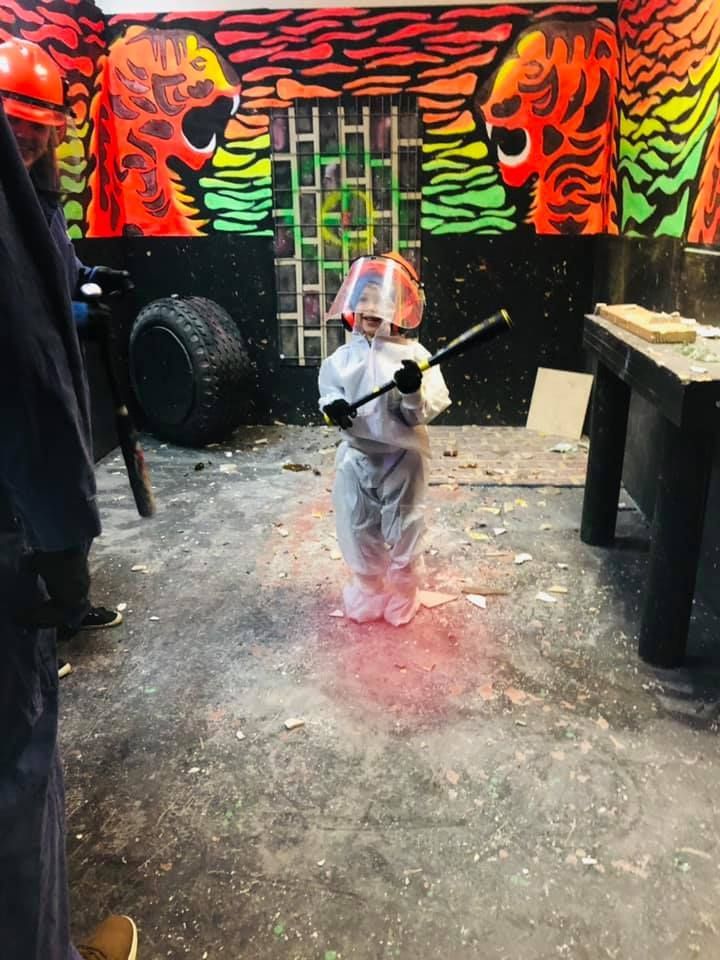A little boy is holding a hammer in a room with graffiti on the wall.