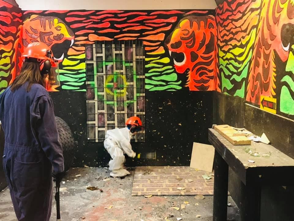 A woman is holding a hammer in a room with graffiti on the walls.