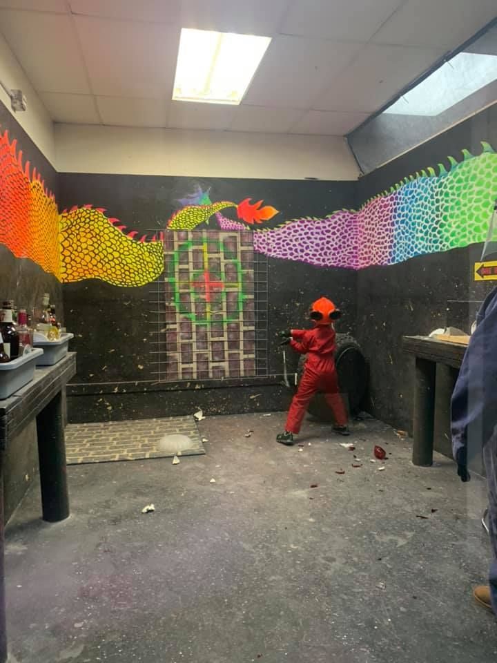 A child is standing in a room with a painting of a dragon on the wall.