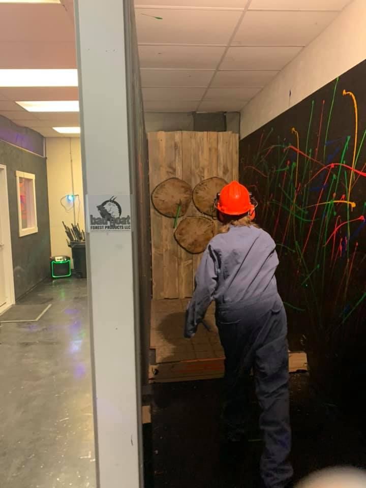 A person wearing a hard hat is throwing axes at a wall.