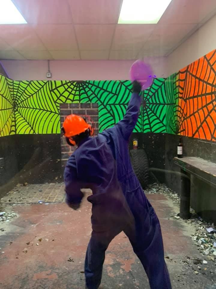 A man wearing a hard hat is standing in a room with spider webs painted on the walls