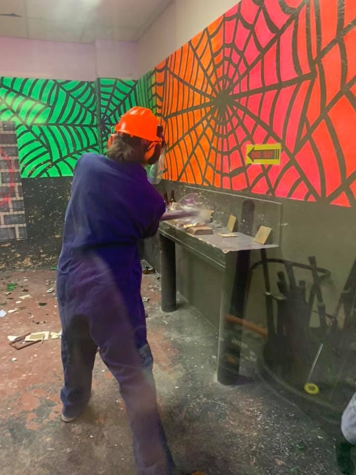 A man wearing a hard hat is standing in a room with a spider web on the wall.