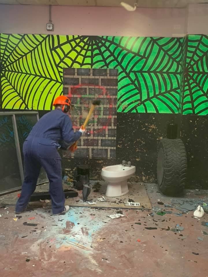 A man is using a hammer to smash a toilet in a bathroom