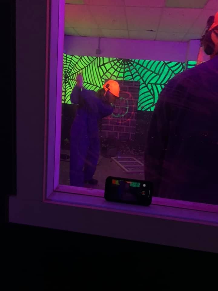 A man is standing in front of a glow in the dark wall.