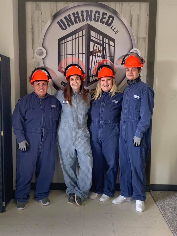 A group of people wearing blue jumpsuits and hard hats are posing for a picture.