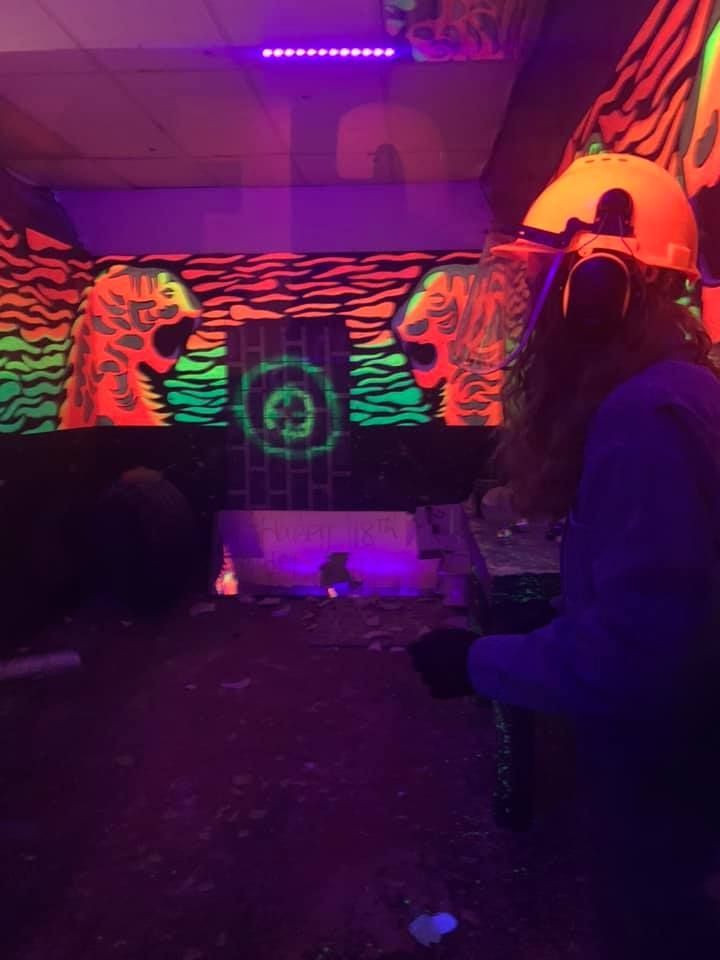 A woman is sitting in front of a glow in the dark wall.