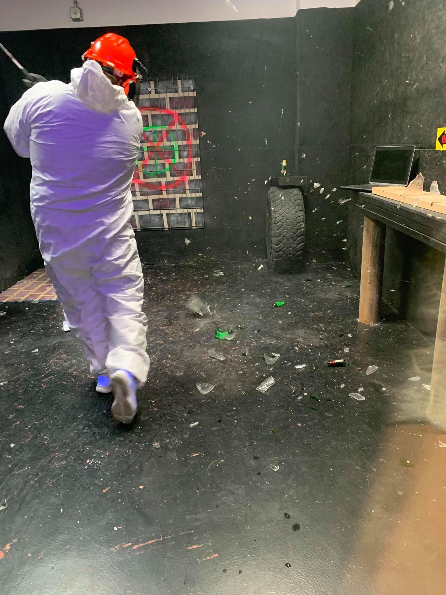 A man in a white suit is standing in a room with a hammer.