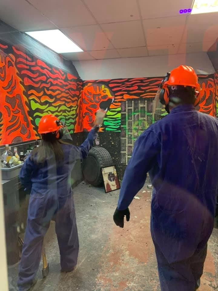 A man and a woman wearing hard hats are standing in a room.