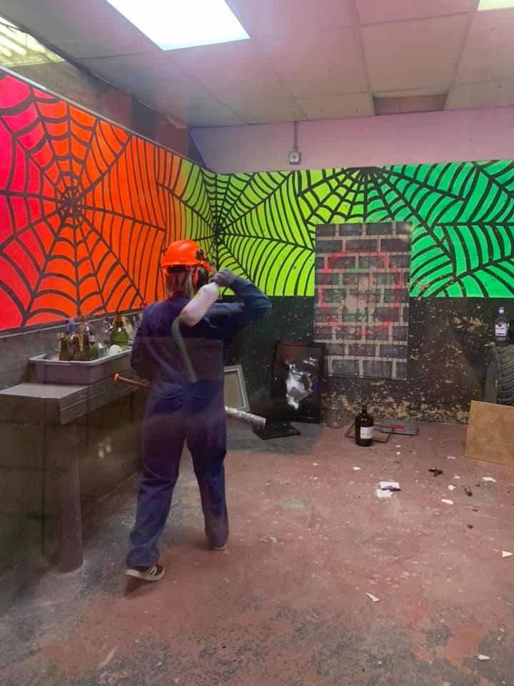 A man in a hard hat is standing in a room with spider webs painted on the walls.