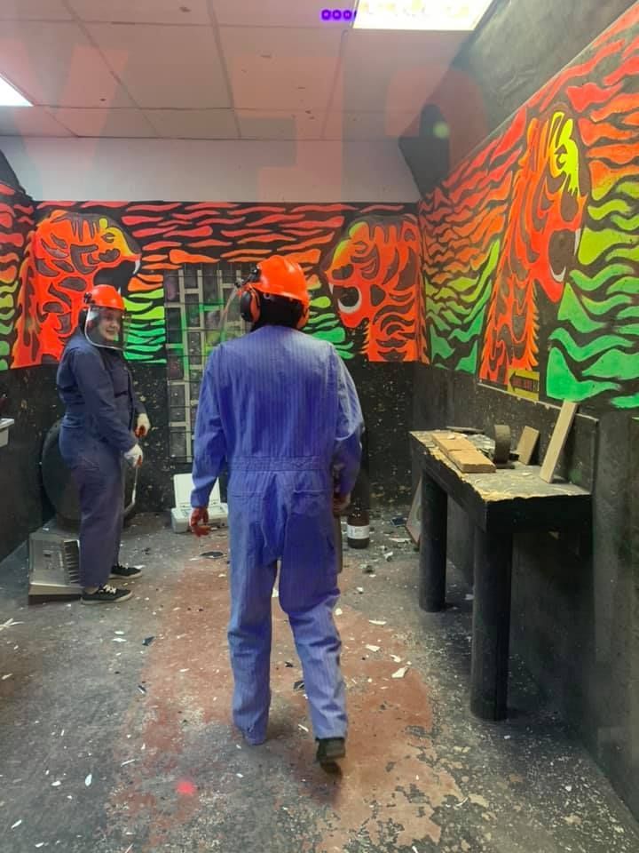 A group of people are standing in a room with a mural on the wall.