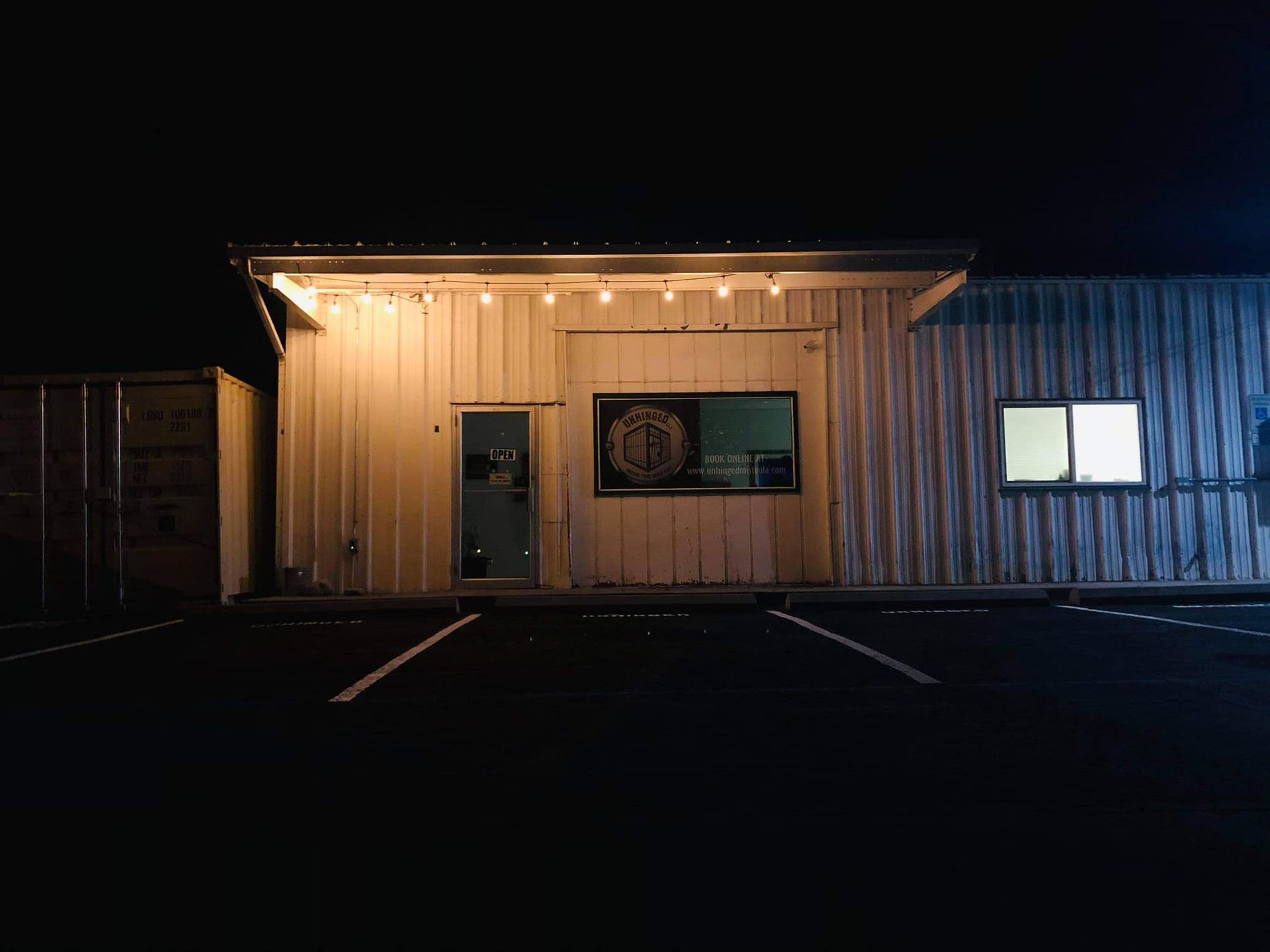 A building is lit up at night with a parking lot in front of it.